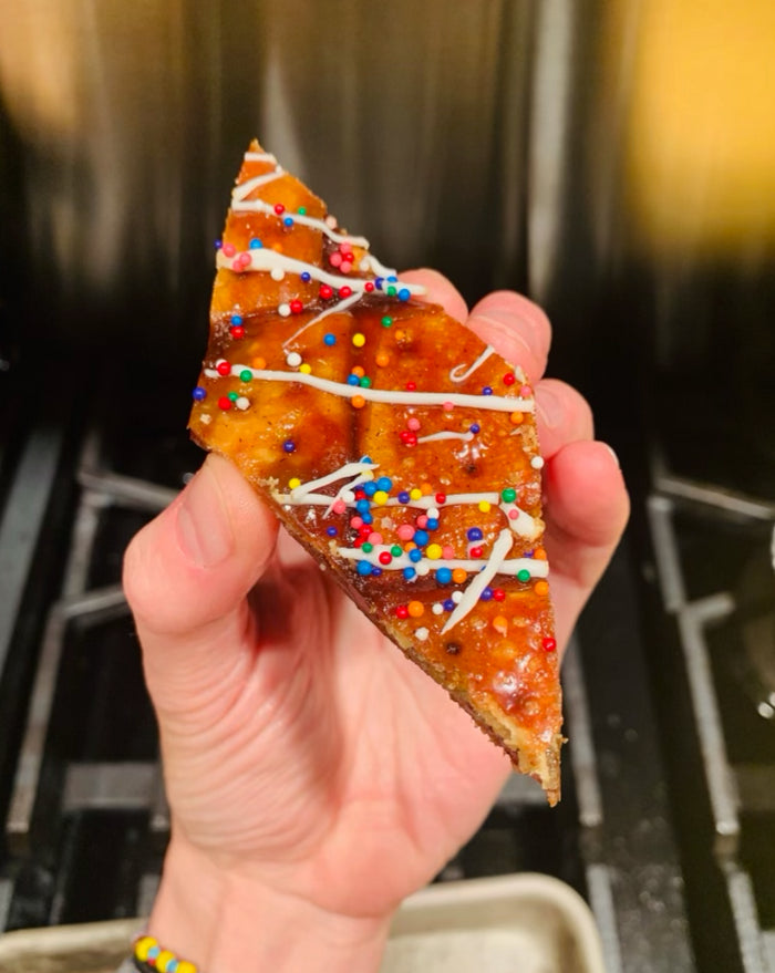 A hand holding a piece of gingerbread toffee