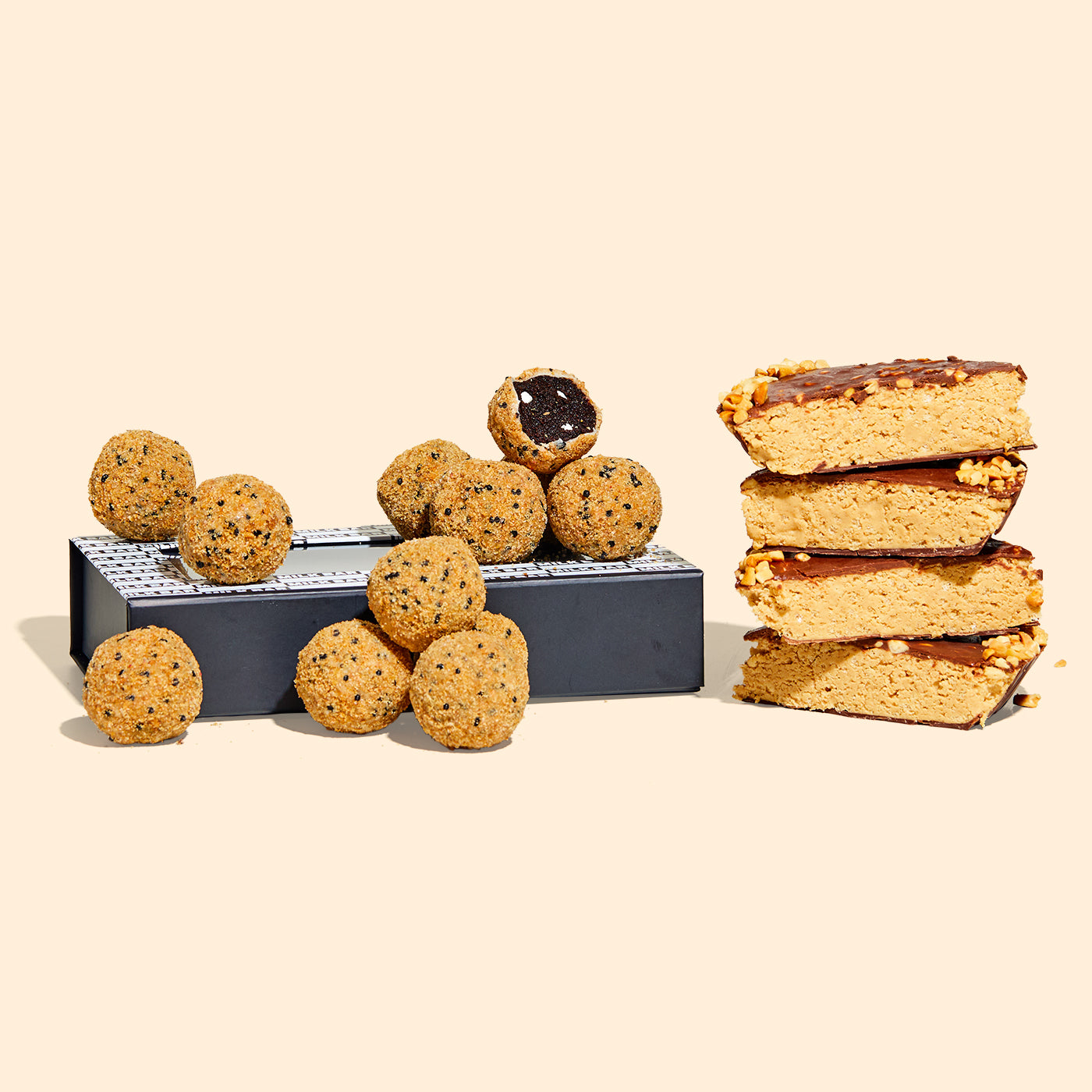 A giftable branded dozen box of s'mores cake truffles beside a stack of chocolate peanut butter crunch pie slices stacked.