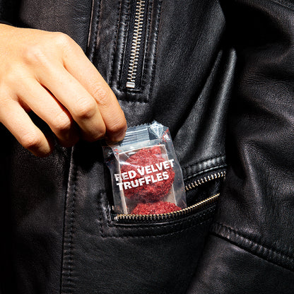 A close up view of the pocket on a jacket with a 3-pack of red velvet cheesecake truffles nestled inside