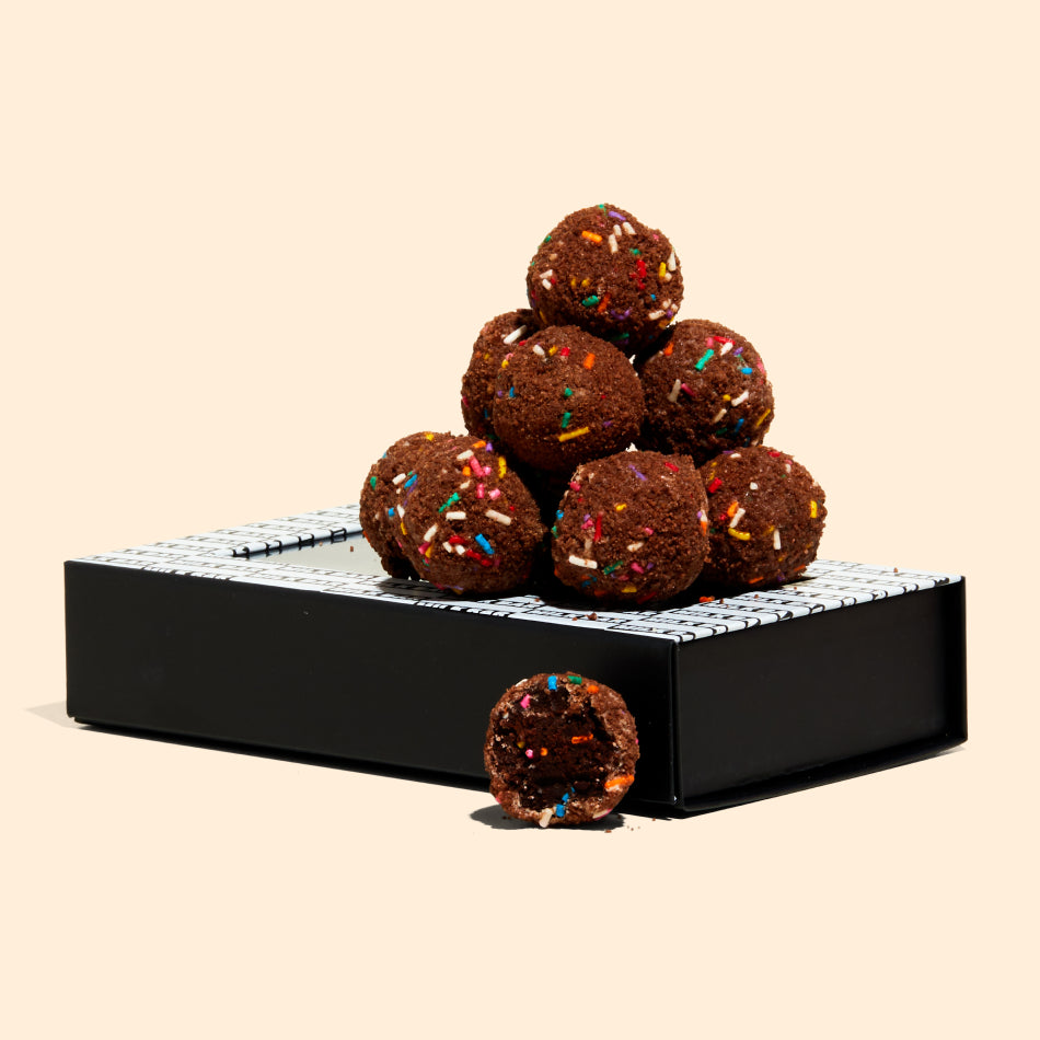 A pile of chocolate birthday cake truffles sitting on top of their packaging.